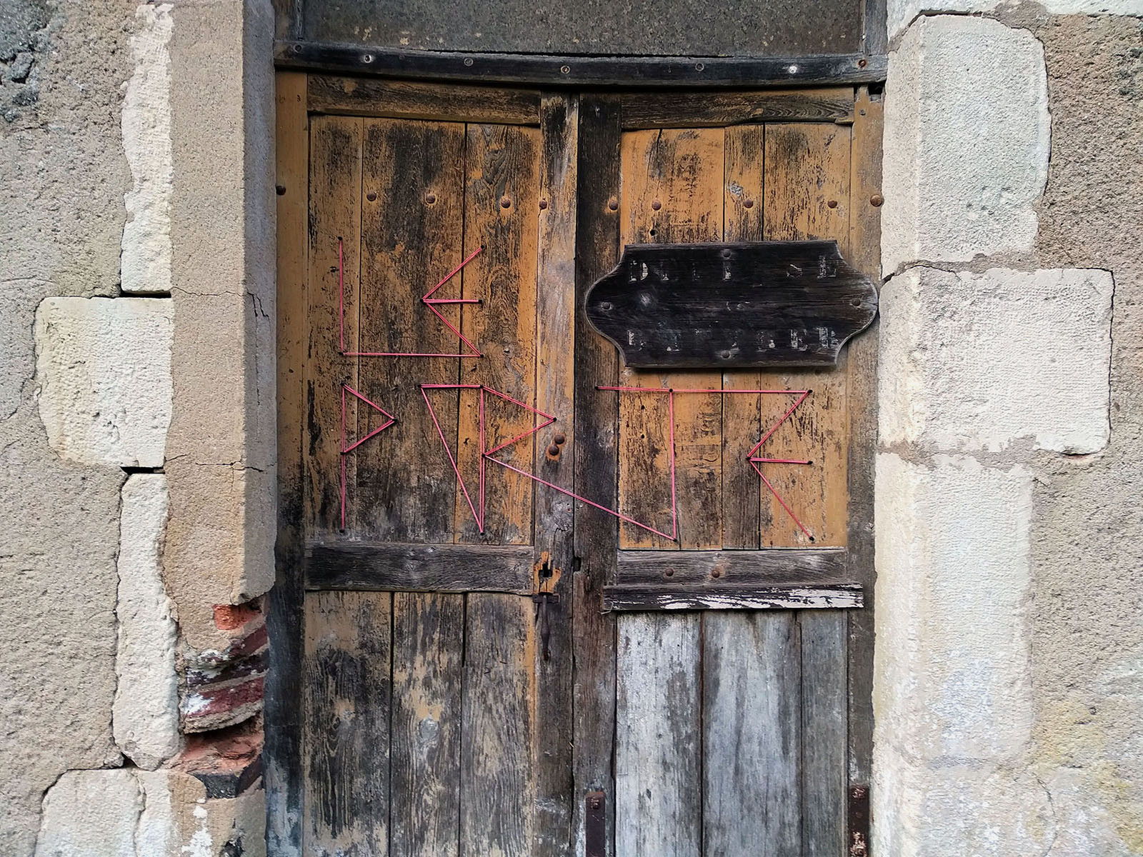 A word formed by pink cord on old wooden doors